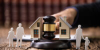 Close-up Of Mallet Showing Separation Of Family And House On Reflective Desk